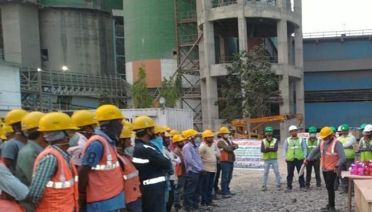Site crew in hard hats and safety vests at a safety briefing